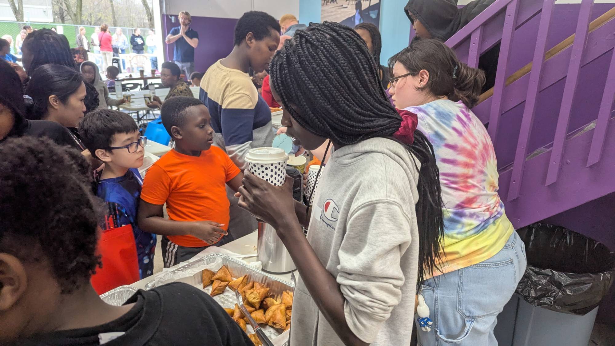 Children of various ages being served food from a buffet line
